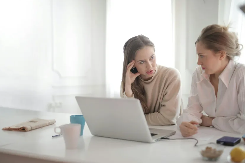 Two women talking through options together at a laptop