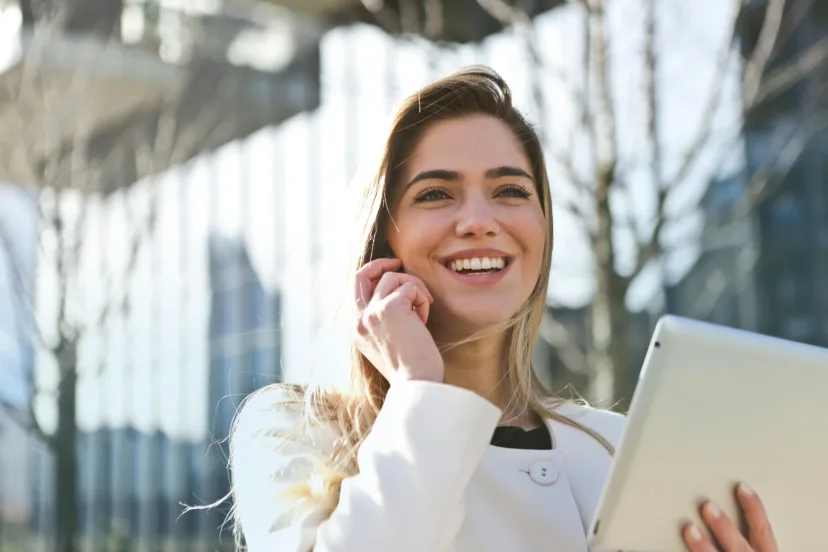 A woman on the phone holding a tablet outdoors