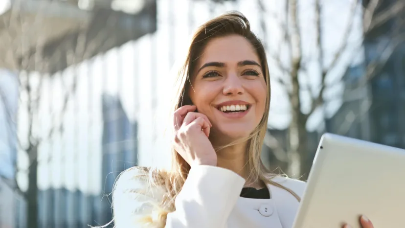 A woman on the phone holding a tablet outdoors