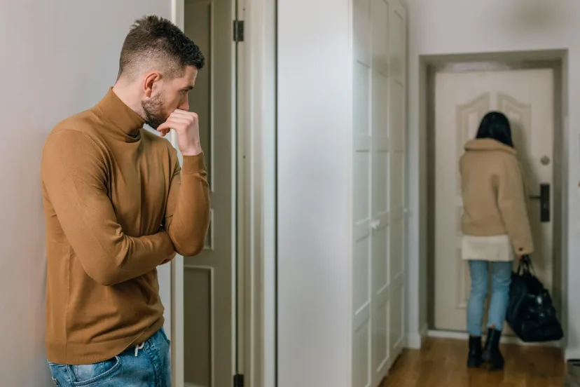 A man standing in a hallway as someone leaves