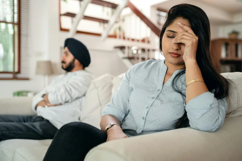 A couple sitting apart on a sofa, looking away from each other