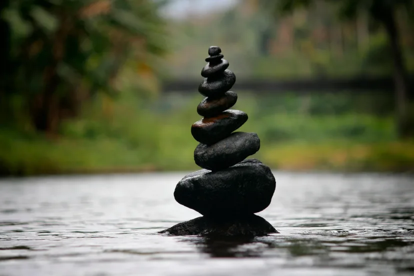 Smooth stones stacked in a cairn above still water
