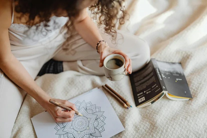 A woman writing in a journal with a cup of coffee