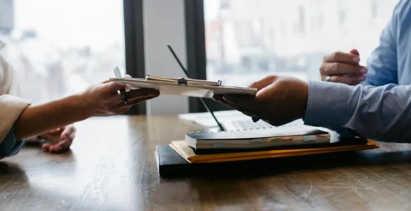 A laptop being handed across a table during a session